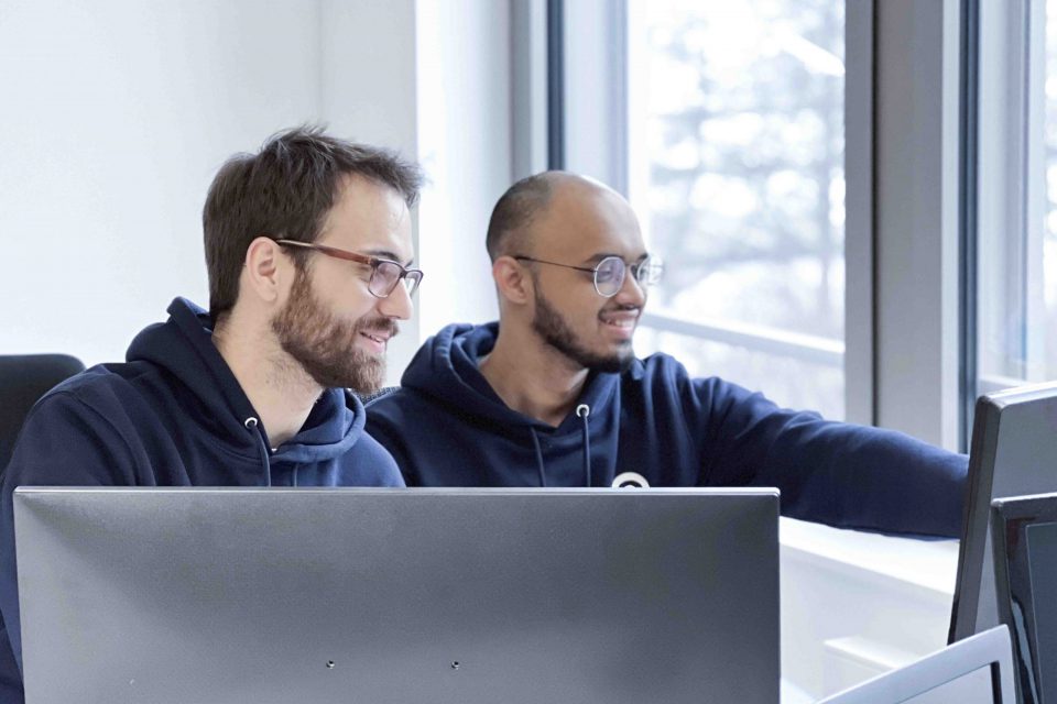 two young men with developer jobs looking and smiling at a screen