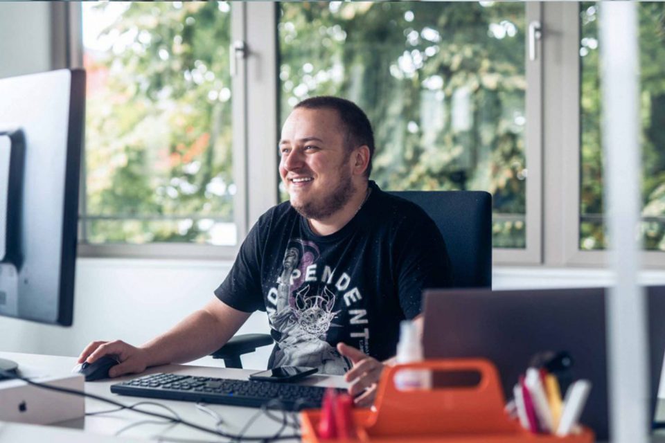 young man smiling at screen in office