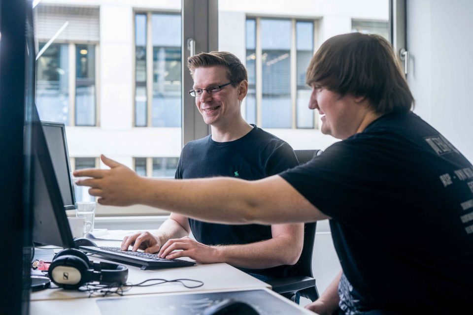 two men in an office looking and pointing at a computer screen