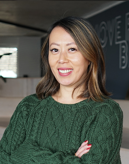 young brunette woman in green jumper smiling at camera