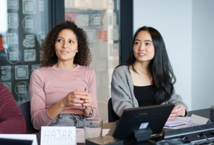 two young adtech business women in a conference smiling