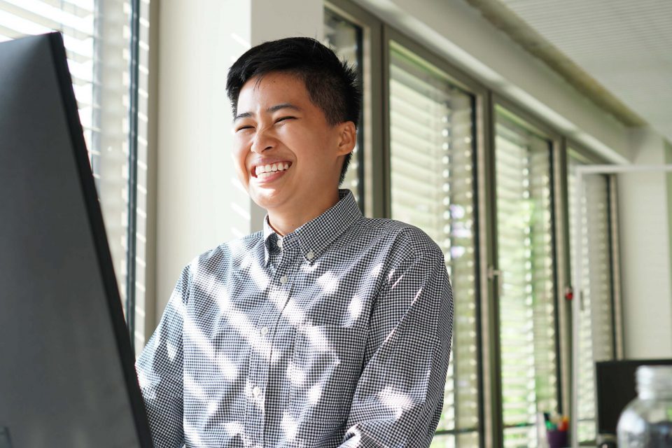 young person working in adtech business team laughing at monitor in office