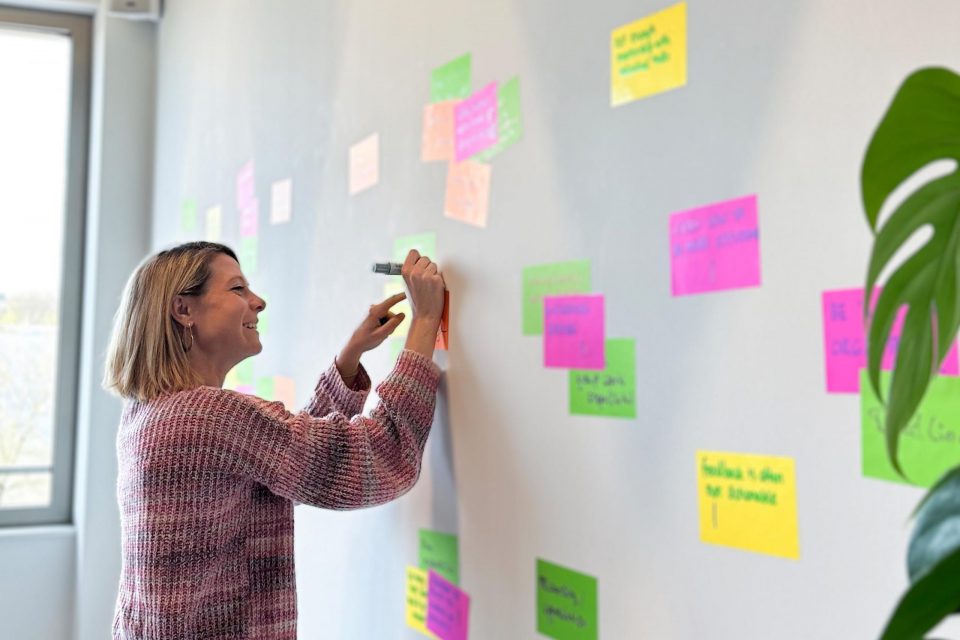 young woman from adtech marketing team smiling and writing something down on a board
