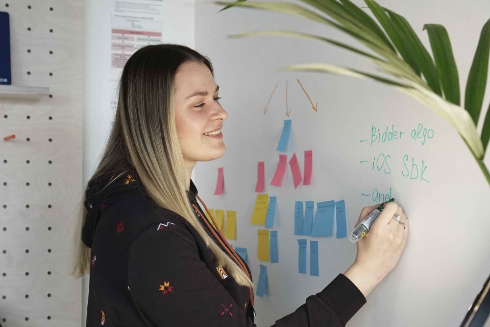 young woman smiling and writing on whiteboard