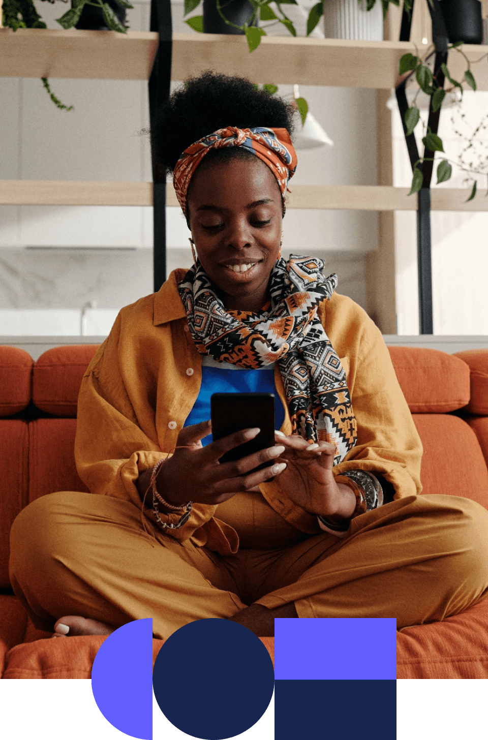 young woman sat on a sofa looking down at her phone and smiling