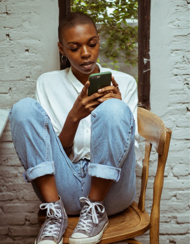 image of young woman looking down at her phone sat on a chair